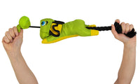 Hands holding a Hyper Pet Flying Pig Interactive Dog Toy by Hyperpet, showcasing a green and yellow plush pig with blue eyes on a black rope. This slingshot-style toy is durable and perfect for active play.