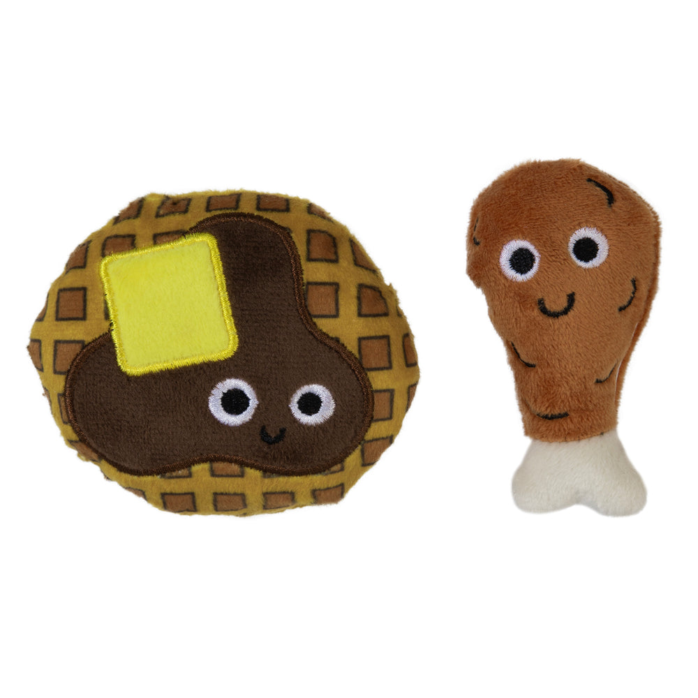 The Mad Cat Chicken and Waffles Twin Pack Catnip & Silvervine Cat Toy features plush waffle with syrup and butter, and drumstick toys. These adorable items have embroidered eyes, cute smiling faces, and are filled with catnip to entertain your feline on a plain white background.