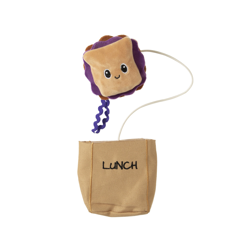 The Quirky Kitty Peanut Butter and Jelly Hide-A-Toy Cat Toy by Quirky Kitty is a brown and purple sandwich plush with a smiling face, attached to a pouch labeled LUNCH. Infused with catnip, it offers mental stimulation for your cats playtime.