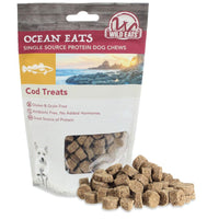 A package of Wild Eats Cod Treats for dogs is displayed. It features sustainable North Atlantic cod and emphasizes single-source protein. It is highlighted as gluten-free, grain-free, and antibiotic-free. Beside the package are brown treat cubes rich in Omega-3 fatty acids.