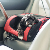 A small dog relaxes inside the Gen7Pets Red Geometric Roller-Carrier by Gen7 on a car seat, looking out through an opening with the cars interior providing a cozy journey.